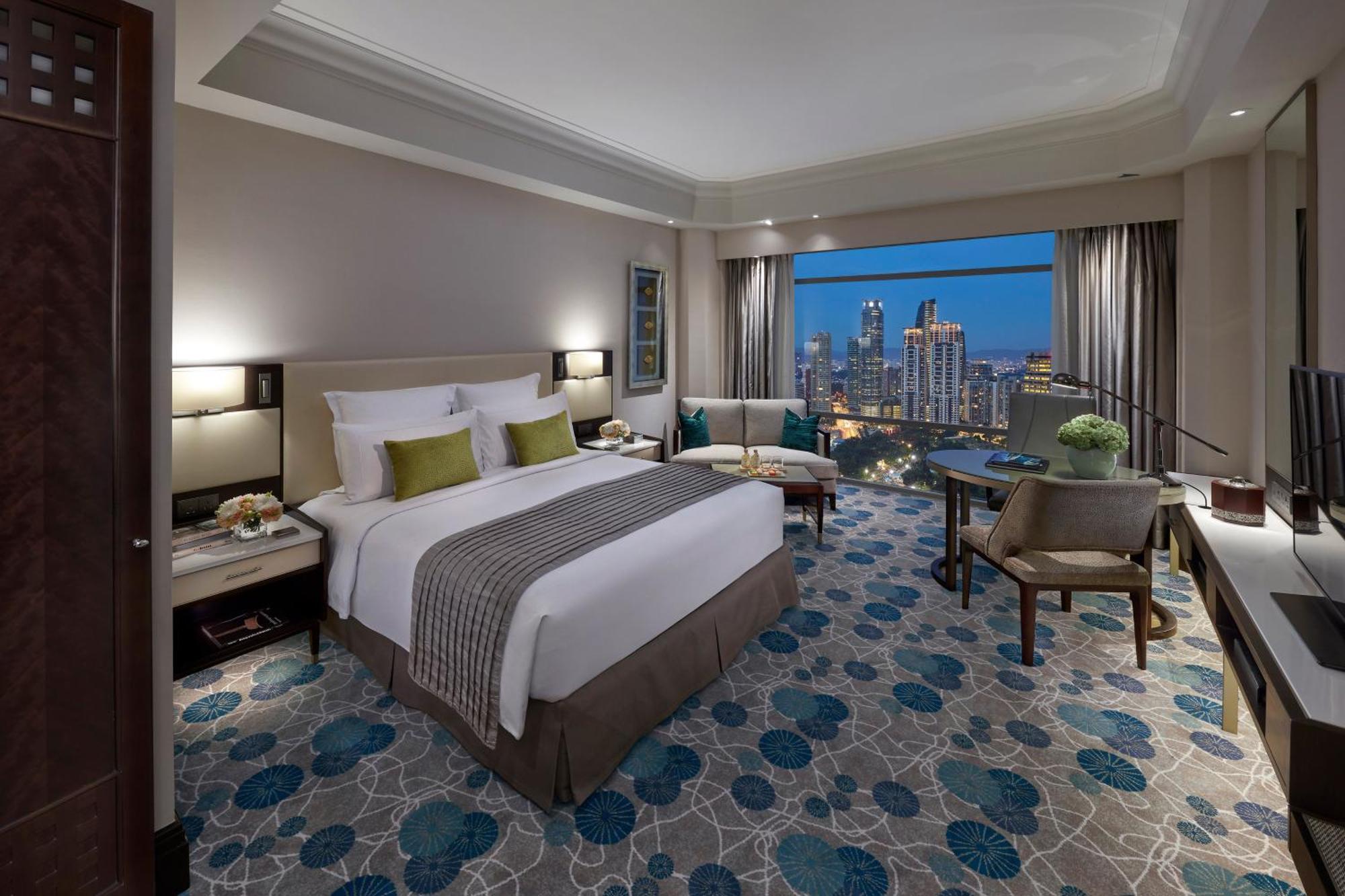 מלון Mandarin Oriental, קואלה לומפור מראה חיצוני תמונה The image shows a luxurious hotel room featuring a king-size bed with white linens and decorative pillows in shades of green. The room has elegant furnishings, including a chair and table arrangement, and large windows that provide a stunning view of