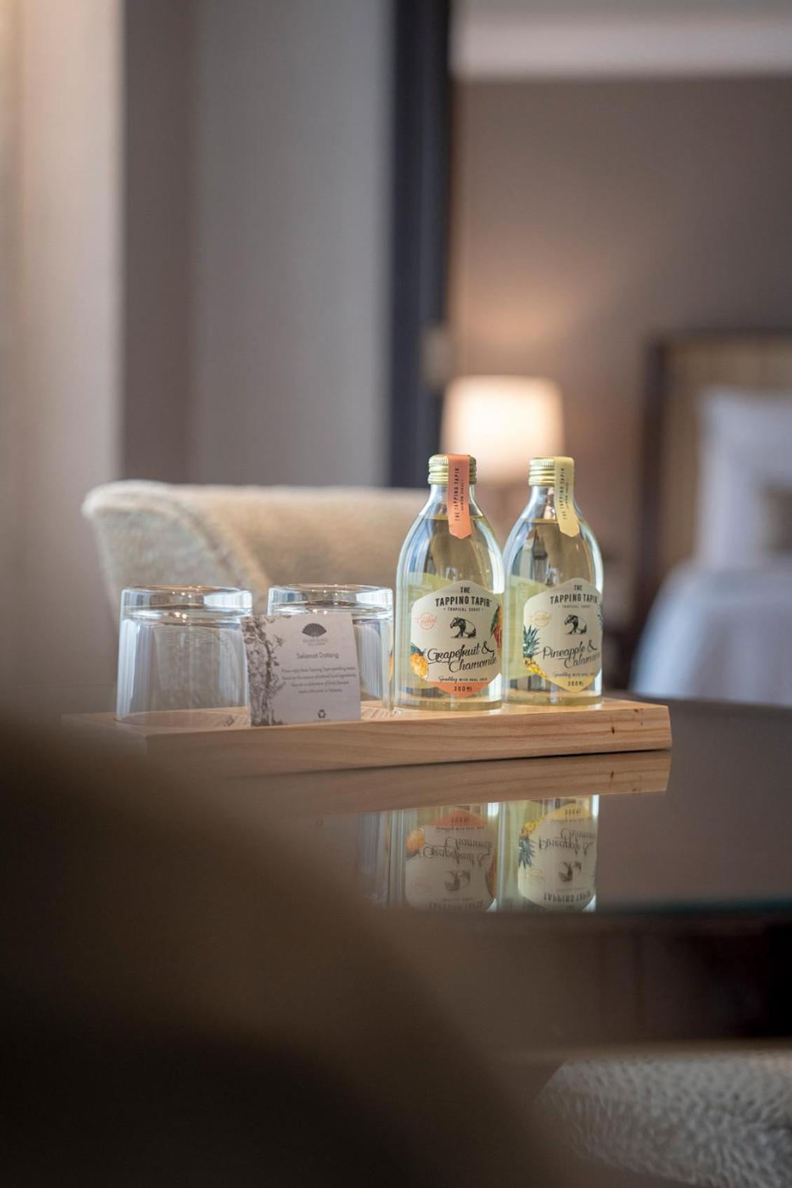 מלון Mandarin Oriental, קואלה לומפור מראה חיצוני תמונה The photo shows a small wooden tray on a table. On the tray, there are two glass bottles of beverages labeled "Crisp & Clean," and two clear drinking glasses. There's also a small card or piece of paper, possibly providing information or a menu. The 