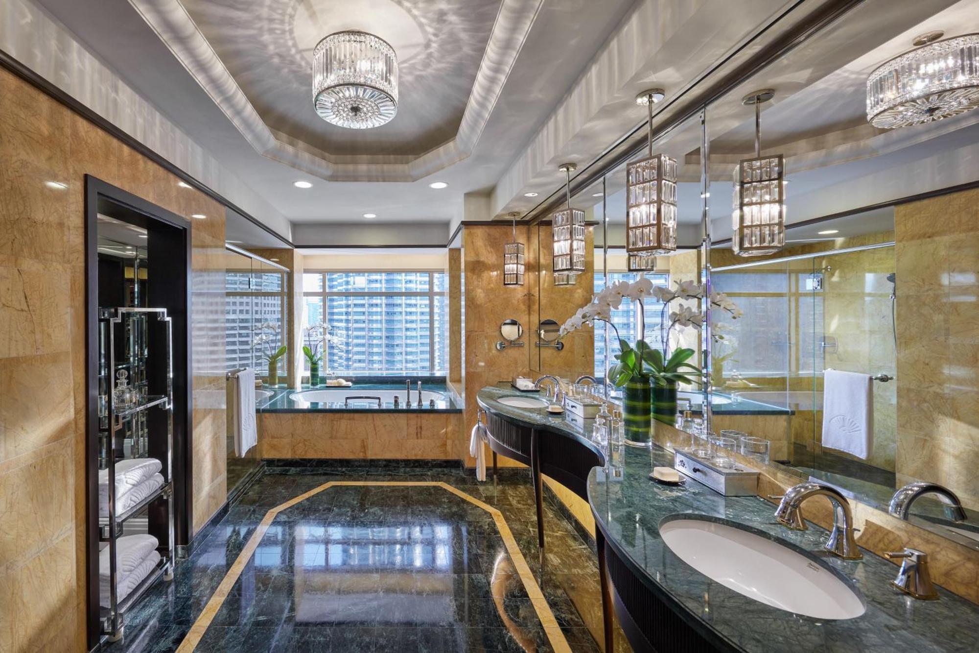 מלון Mandarin Oriental, קואלה לומפור מראה חיצוני תמונה The image shows a luxurious and modern bathroom. It features a polished dark green marble floor and countertops, complemented by elegant cabinetry. The walls are adorned with light-colored materials, giving a warm and inviting atmosphere. 

There are
