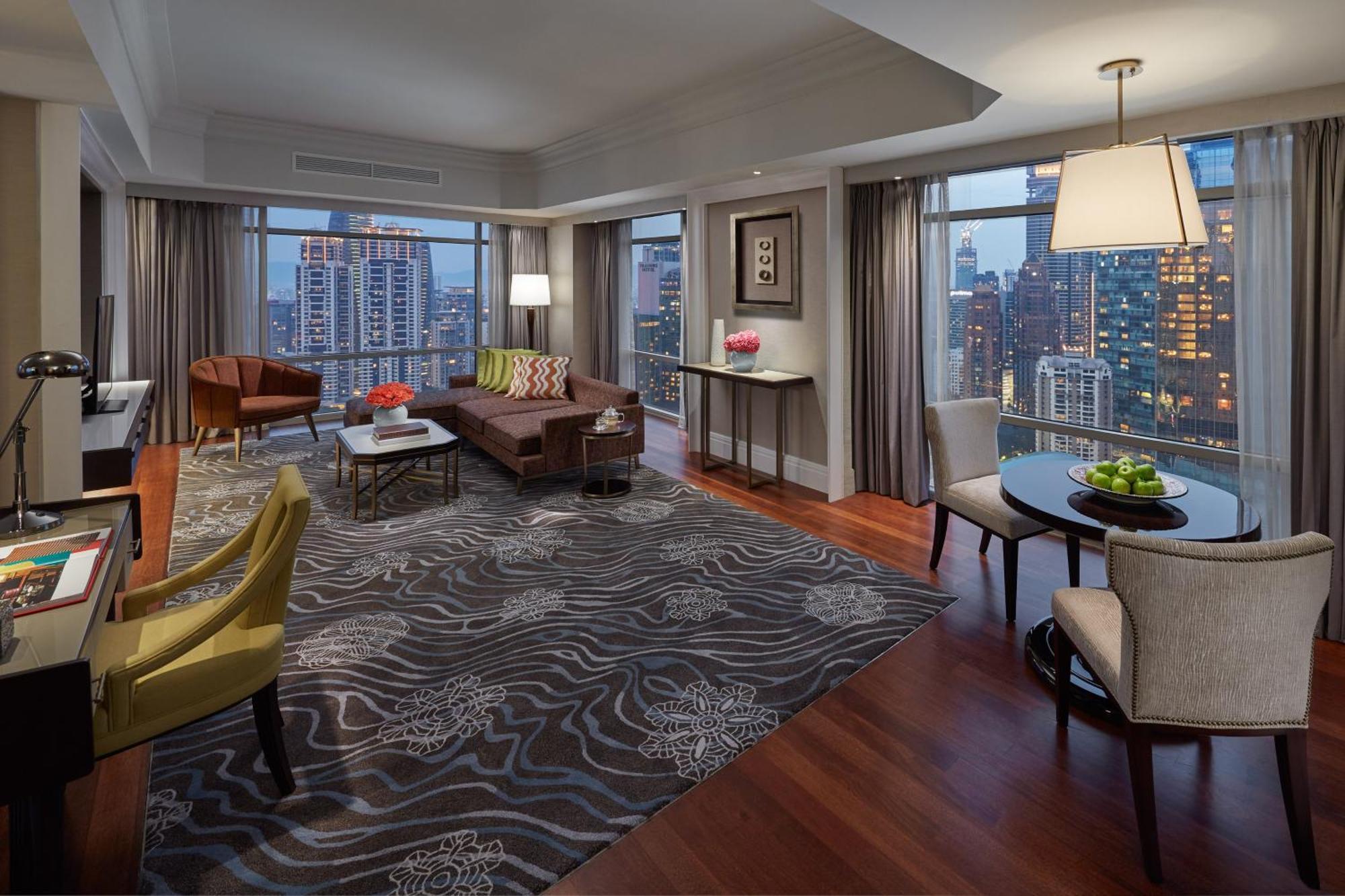 מלון Mandarin Oriental, קואלה לומפור מראה חיצוני תמונה The photo shows a modern and elegantly designed hotel room or living space. It features a spacious layout with large windows that offer a view of a city skyline. The room is decorated with a stylish area rug that has a wavy pattern, and there are com