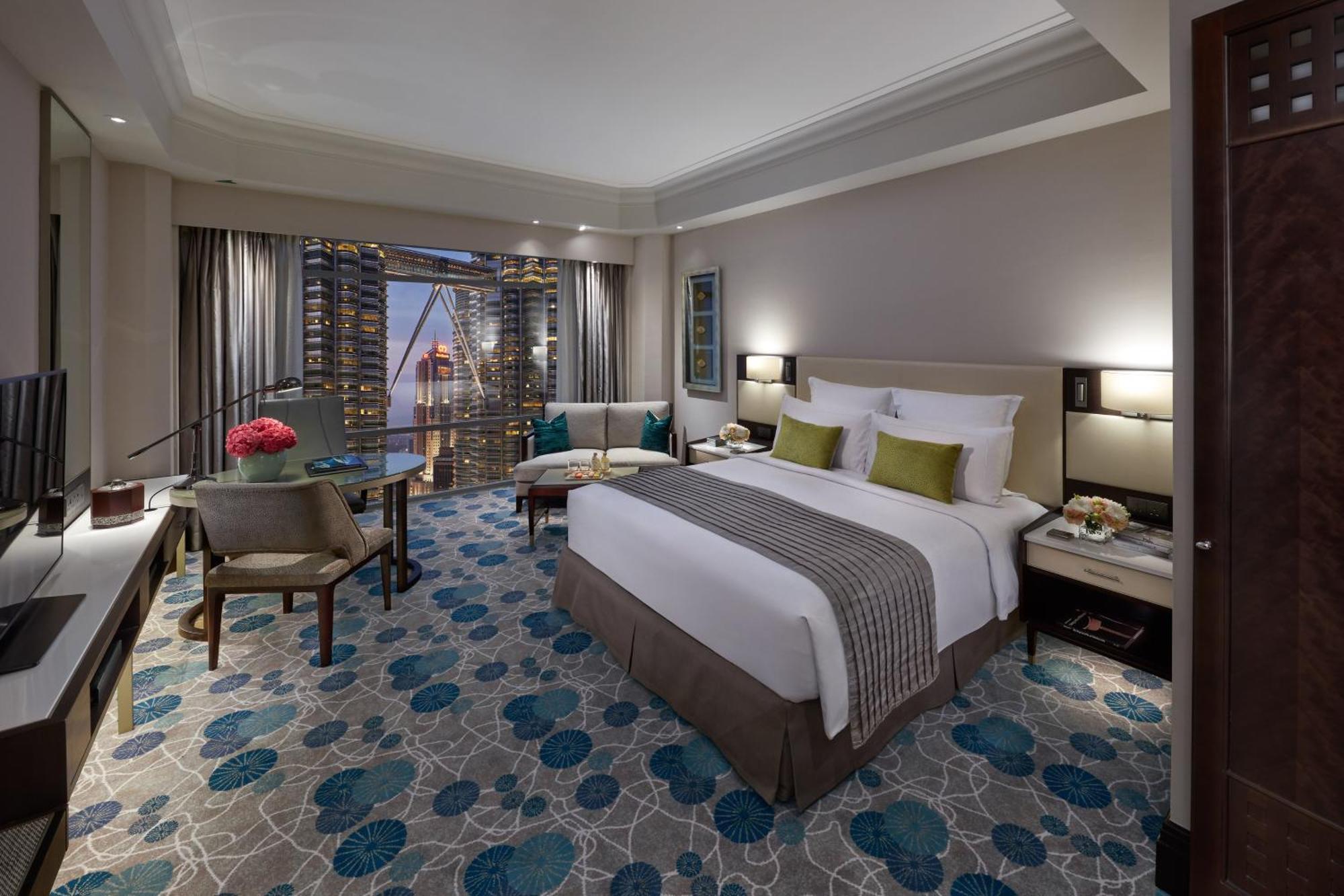 מלון Mandarin Oriental, קואלה לומפור מראה חיצוני תמונה The photo shows a well-designed hotel room featuring a large bed with white linens and green accent pillows. The room has a modern and elegant style, with two armchairs and a small table arranged near a window. There are decorative elements such as a