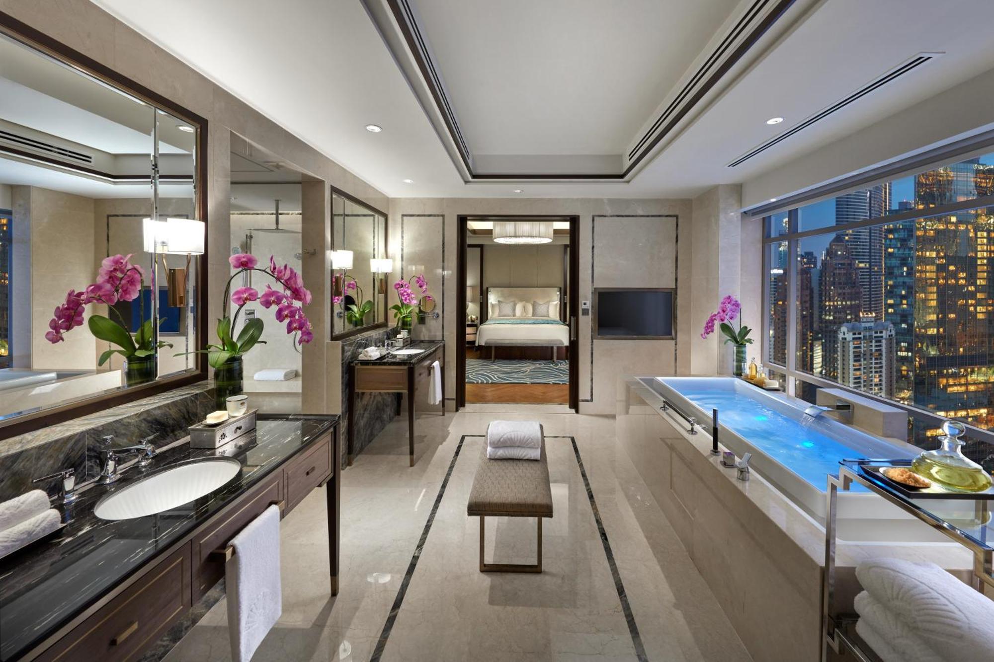 מלון Mandarin Oriental, קואלה לומפור מראה חיצוני תמונה The photo shows a luxurious bathroom featuring modern design elements. There are elegant dark stone countertops with a double sink setup and stylish fixtures. Large mirrors are mounted on the walls, reflecting the spacious area. Bright orchids in vas