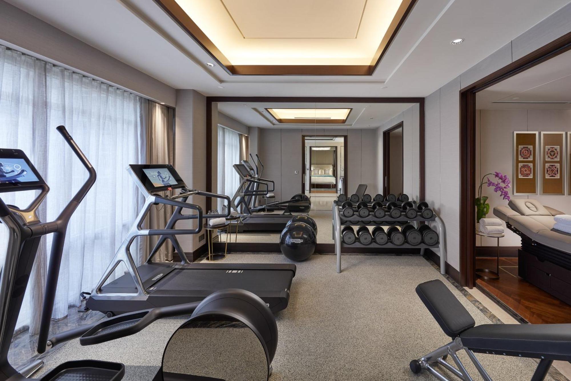מלון Mandarin Oriental, קואלה לומפור מראה חיצוני תמונה The photo shows a modern gym or workout space. It features several pieces of exercise equipment, including a treadmill and an elliptical machine. There are also weights, indicated by a rack of dumbbells. The room has a sleek and sophisticated design 