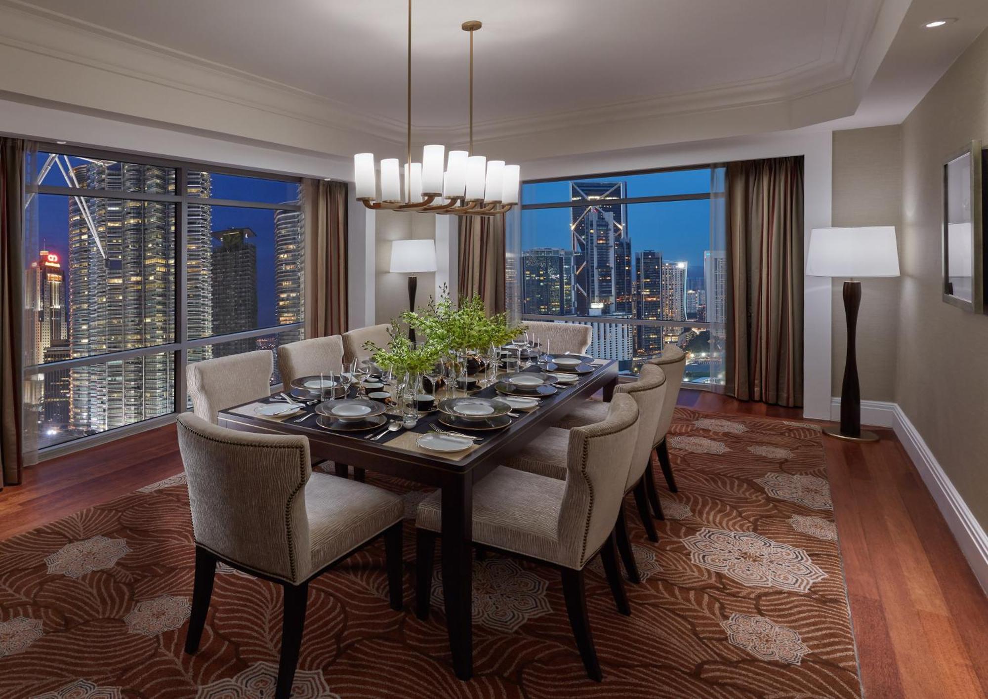 מלון Mandarin Oriental, קואלה לומפור מראה חיצוני תמונה The photo shows an elegantly designed dining room. It features a long, dark wooden dining table surrounded by upholstered chairs. The table is set with dishes, cutlery, and a charming centerpiece of green foliage. Overhead, a stylish chandelier provi