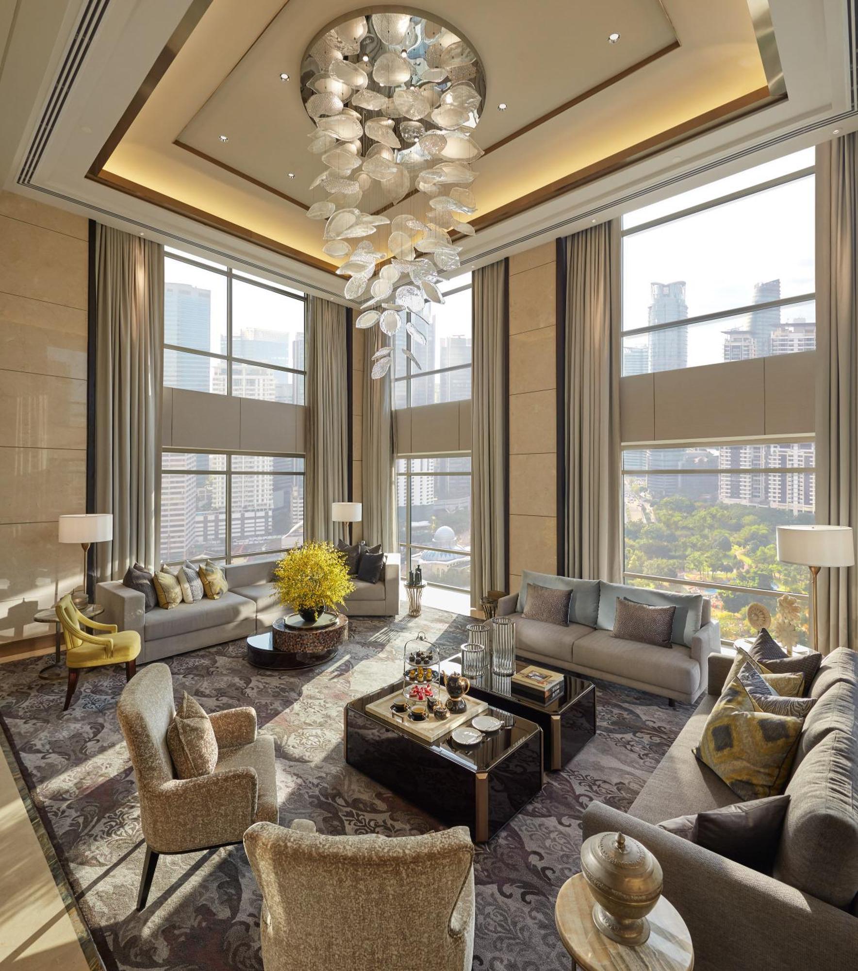 מלון Mandarin Oriental, קואלה לומפור מראה חיצוני תמונה The photo depicts a stylish and modern living room featuring large windows that allow plenty of natural light. The space is elegantly decorated with a contemporary chandelier hanging from the ceiling. There are two comfortable sofas in neutral tones,