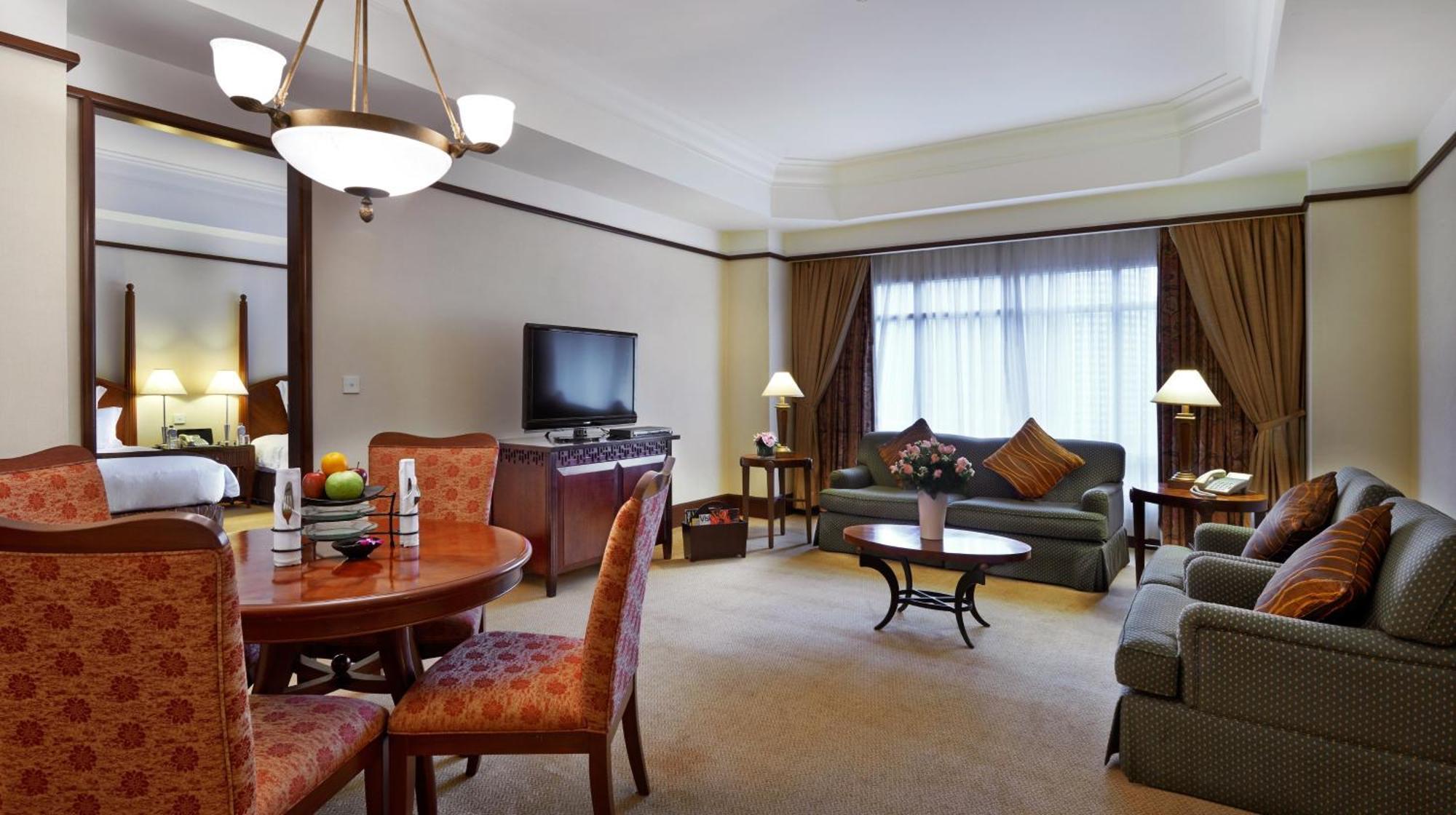 מלון Mandarin Oriental, קואלה לומפור מראה חיצוני תמונה The photo shows an inviting hotel suite. It features a spacious living area with a comfortable green sofa and a couple of armchairs. There’s a round dining table with four chairs. A flat-screen TV is mounted on the wall, and there are lamps on variou
